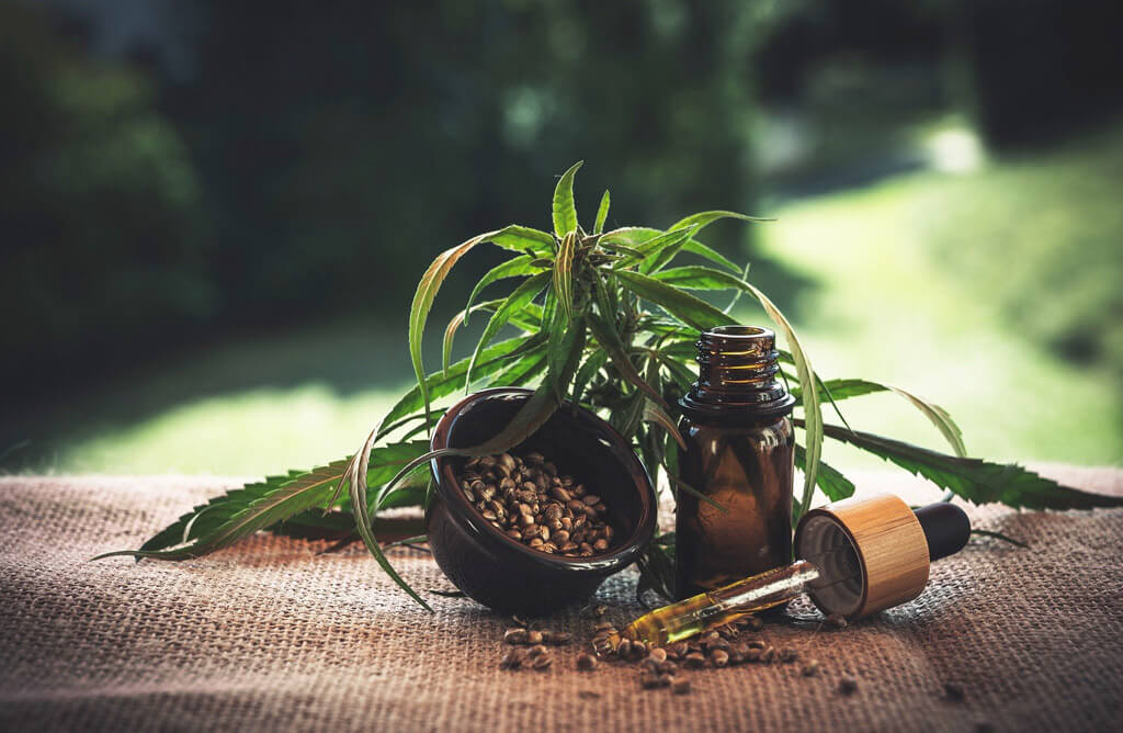 CBD : bouteille de CBD avec gouttes et feuilles de cannabis en arrière-plan