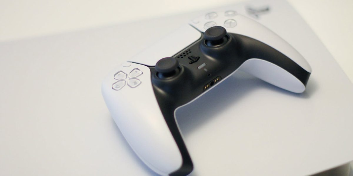 manette PS5 sur PS4 : manette de Playstation 5 à côté d'une console PS4